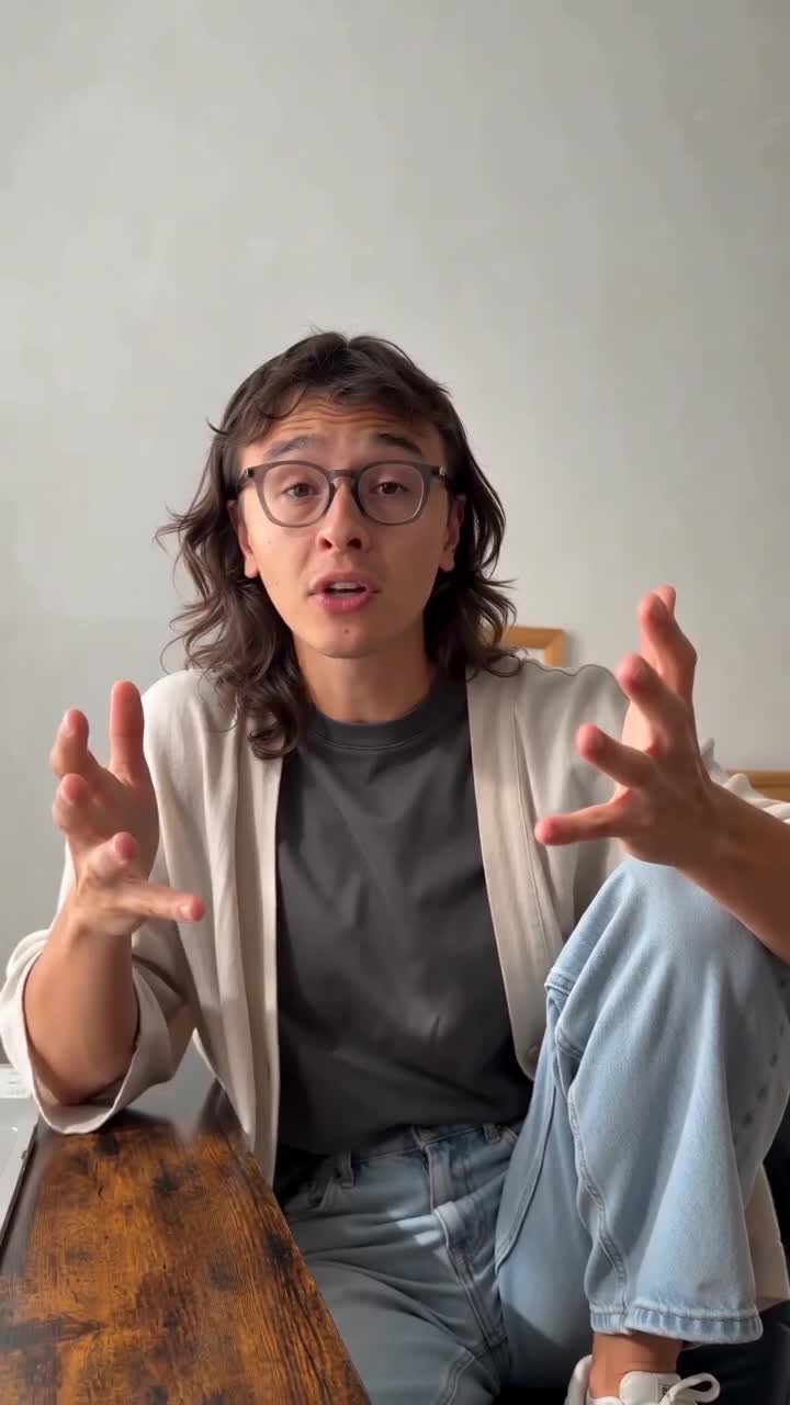 A creator indoors making expressive hand gestures toward the camera